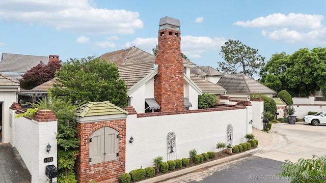 4817 S Yorktown Pl, Tulsa, OK 74105 - view of side of property with concrete driveway, stucco siding, a tile roof, a chimney, and brick siding