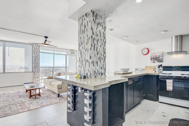 450 W 7th St Unit 1405, Tulsa, OK 74119 - kitchen featuring gas stove, wall chimney range hood, finished concrete flooring, and open floor plan