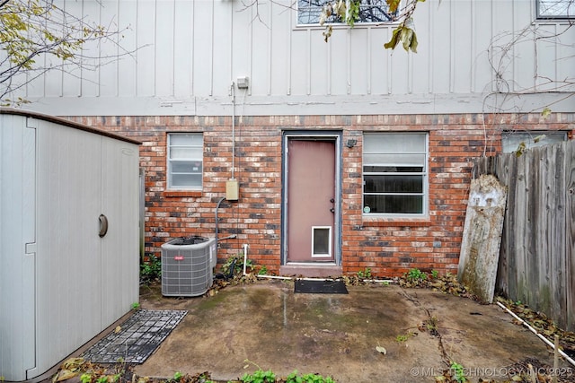 5342 E 47th Pl S Unit 1, Tulsa, OK 74135 - doorway to property with brick siding, central AC, a patio area, and board and batten siding