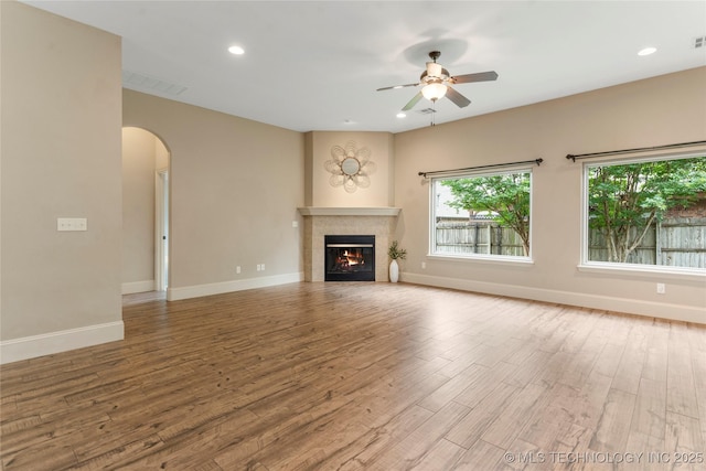 4675 E 144th Pl S, Bixby, OK 74008 - unfurnished living room featuring wood finished floors, ceiling fan, a fireplace, baseboards, and arched walkways