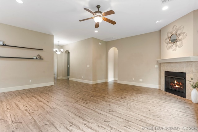 4675 E 144th Pl S, Bixby, OK 74008 - unfurnished living room with arched walkways, wood finished floors, a ceiling fan, a tile fireplace, and recessed lighting