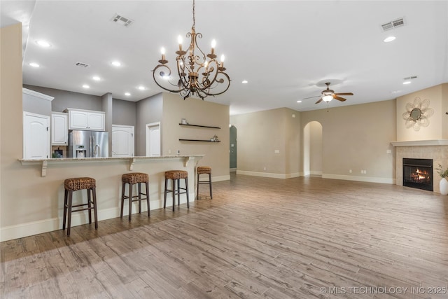 4675 E 144th Pl S, Bixby, OK 74008 - kitchen with stainless steel refrigerator with ice dispenser, arched walkways, a breakfast bar area, a ceiling fan, and light wood-style flooring