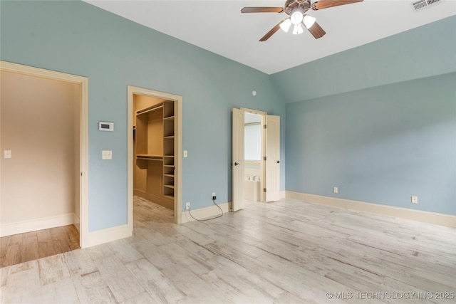 4675 E 144th Pl S, Bixby, OK 74008 - unfurnished bedroom with a walk in closet, wood finished floors, vaulted ceiling, a closet, and baseboards
