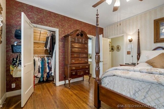 2403 S Troost Ave, Tulsa, OK 74114 - bedroom with wallpapered walls, wood finished floors, baseboards, a closet, and a ceiling fan