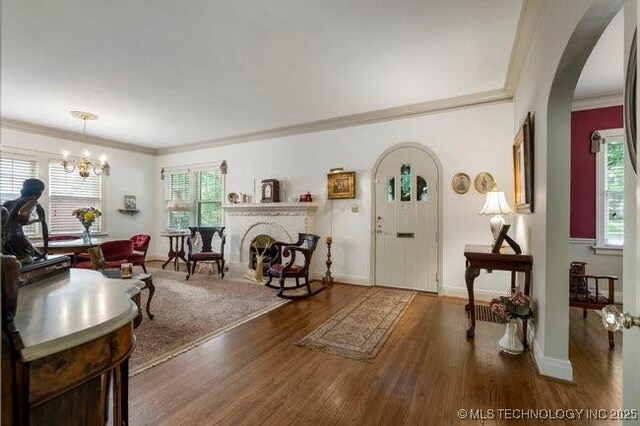 2403 S Troost Ave, Tulsa, OK 74114 - living room with arched walkways, crown molding, plenty of natural light, a chandelier, and wood finished floors