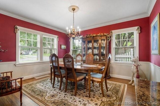 2403 S Troost Ave, Tulsa, OK 74114 - dining space featuring healthy amount of natural light, a chandelier, wood finished floors, and crown molding