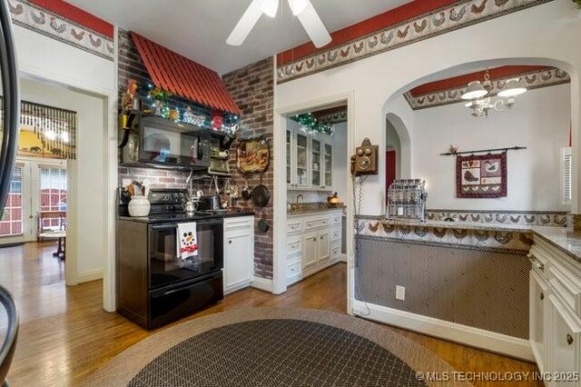 2403 S Troost Ave, Tulsa, OK 74114 - kitchen with black appliances, arched walkways, wood finished floors, and white cabinetry