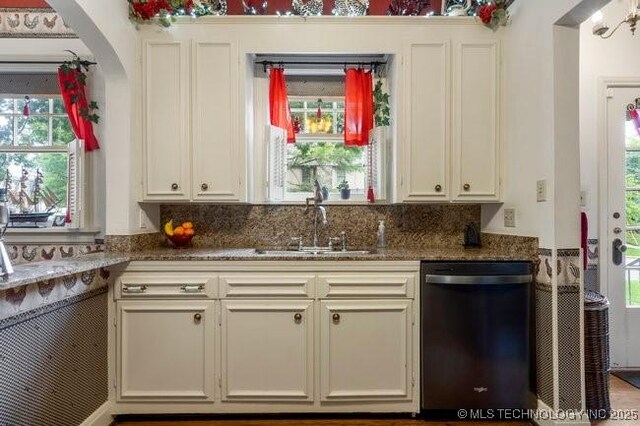 2403 S Troost Ave, Tulsa, OK 74114 - kitchen with dishwasher, a sink, arched walkways, dark stone counters, and white cabinets