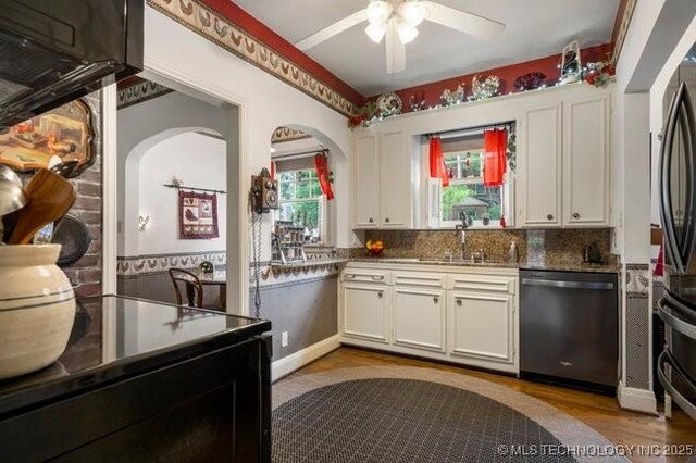 2403 S Troost Ave, Tulsa, OK 74114 - kitchen with appliances with stainless steel finishes, white cabinets, ceiling fan, a sink, and light wood-type flooring