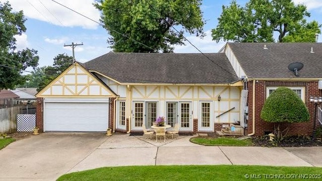 2403 S Troost Ave, Tulsa, OK 74114 - view of front facade with brick siding, french doors, driveway, a garage, and stucco siding