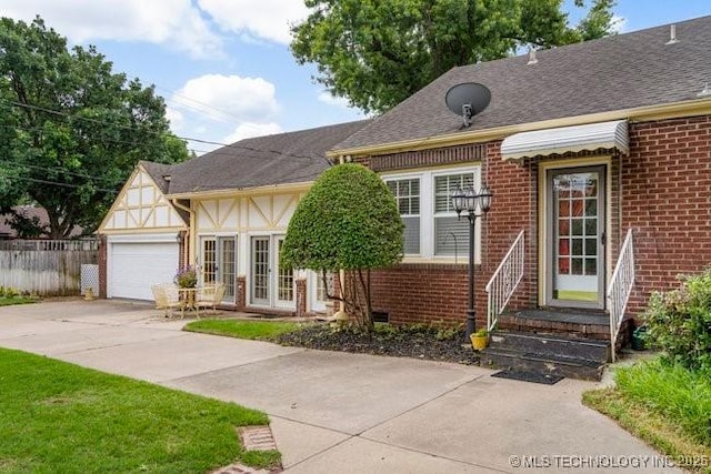 2403 S Troost Ave, Tulsa, OK 74114 - view of front facade with brick siding, concrete driveway, a garage, and french doors