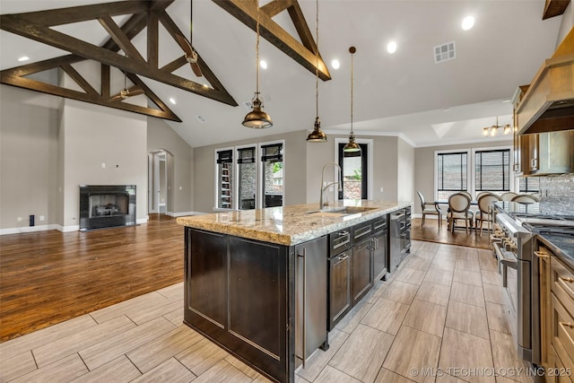 3805 S Tamarack Ave, Broken Arrow, OK 74011 - kitchen featuring a sink, stainless steel appliances, an island with sink, beamed ceiling, and light stone counters