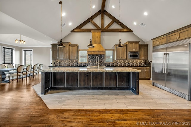 3805 S Tamarack Ave, Broken Arrow, OK 74011 - kitchen featuring stainless steel appliances, a sink, a center island with sink, light stone counters, and tasteful backsplash
