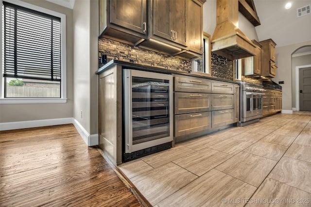3805 S Tamarack Ave, Broken Arrow, OK 74011 - kitchen featuring wine cooler, wall oven, backsplash, dark countertops, and baseboards