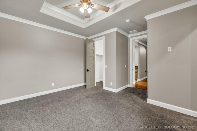 3805 S Tamarack Ave, Broken Arrow, OK 74011 - unfurnished bedroom with dark carpet, a tray ceiling, baseboards, crown molding, and a walk in closet