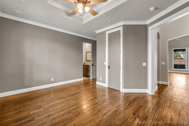 3805 S Tamarack Ave, Broken Arrow, OK 74011 - unfurnished bedroom with arched walkways, wood finished floors, crown molding, baseboards, and a tray ceiling