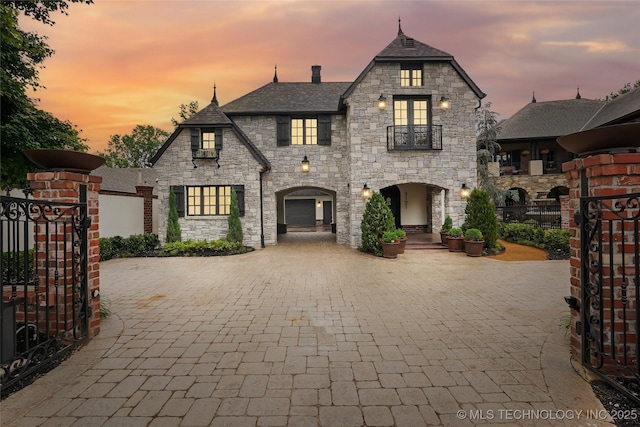 3121 S Rockford Dr, Tulsa, OK 74105 - french country home featuring stone siding, decorative driveway, and a gate