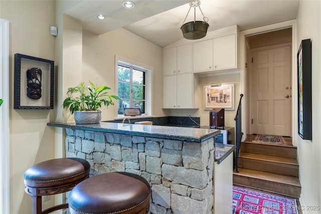 1764 E 30th St, Tulsa, OK 74114 - kitchen featuring white cabinetry, a peninsula, a kitchen bar, dark stone countertops, and recessed lighting