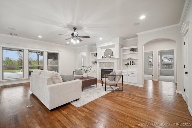 16121 E 78th St, Owasso, OK 74055 - living area with arched walkways, crown molding, a fireplace, a ceiling fan, and wood finished floors
