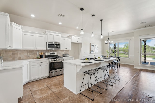 16121 E 78th St, Owasso, OK 74055 - kitchen with appliances with stainless steel finishes, a sink, light tile patterned floors, decorative backsplash, and white cabinetry