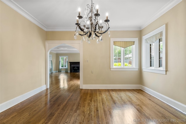 2508 Terwilleger Blvd, Tulsa, OK 74114 - unfurnished dining area featuring arched walkways, wood finished floors, crown molding, baseboards, and a chandelier