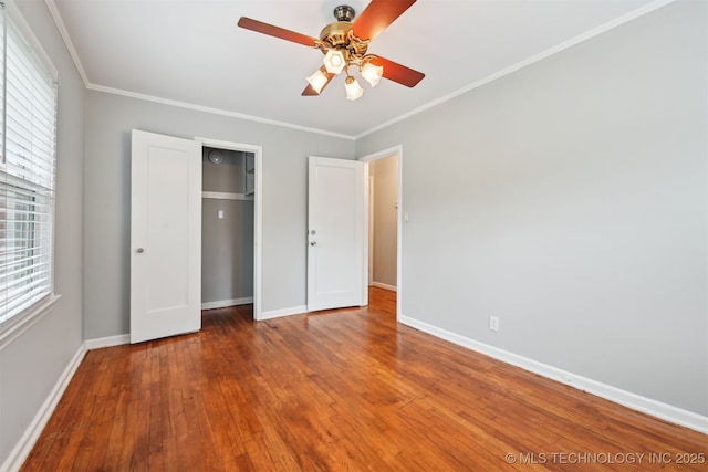 6315 E 5th Pl, Tulsa, OK 74112 - unfurnished bedroom with baseboards, crown molding, multiple windows, hardwood / wood-style floors, and a closet