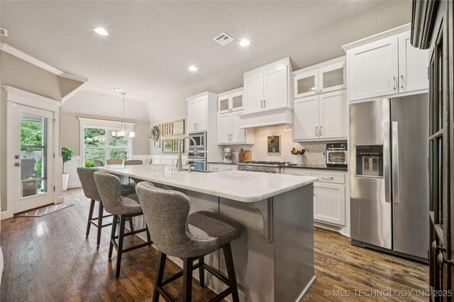 10350 E 122nd St S, Bixby, OK 74008 - kitchen featuring stainless steel appliances, decorative backsplash, white cabinetry, an island with sink, and a breakfast bar area