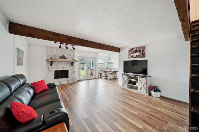 321 W 50th Pl, Sand Springs, OK 74063 - living room featuring beamed ceiling, wood finished floors, a textured ceiling, a stone fireplace, and rail lighting