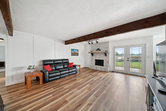 321 W 50th Pl, Sand Springs, OK 74063 - living area featuring beamed ceiling, light wood-style floors, a textured ceiling, french doors, and a decorative wall