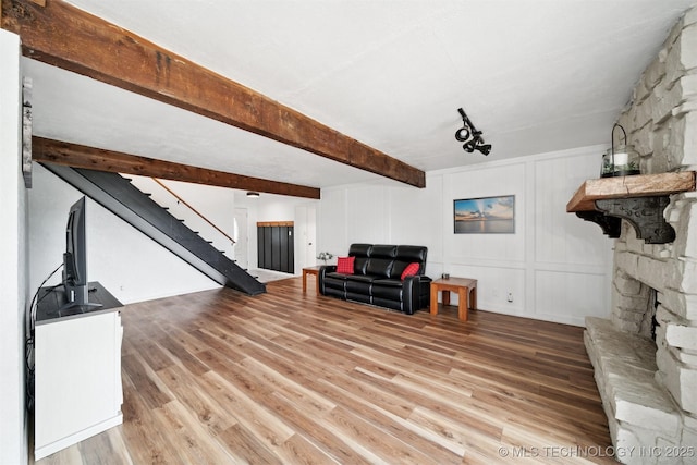 321 W 50th Pl, Sand Springs, OK 74063 - living room featuring wood finished floors, stairs, beam ceiling, and a decorative wall