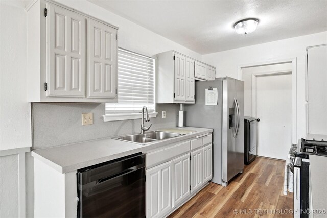 321 W 50th Pl, Sand Springs, OK 74063 - kitchen featuring appliances with stainless steel finishes, a sink, light countertops, white cabinetry, and light wood-style floors