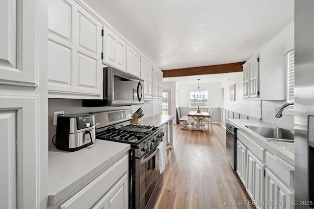 321 W 50th Pl, Sand Springs, OK 74063 - kitchen featuring appliances with stainless steel finishes, a sink, light wood finished floors, white cabinets, and light countertops