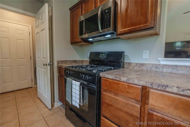 2800 N 20th St, Broken Arrow, OK 74012 - kitchen featuring black gas stove, stainless steel microwave, light tile patterned floors, and brown cabinets