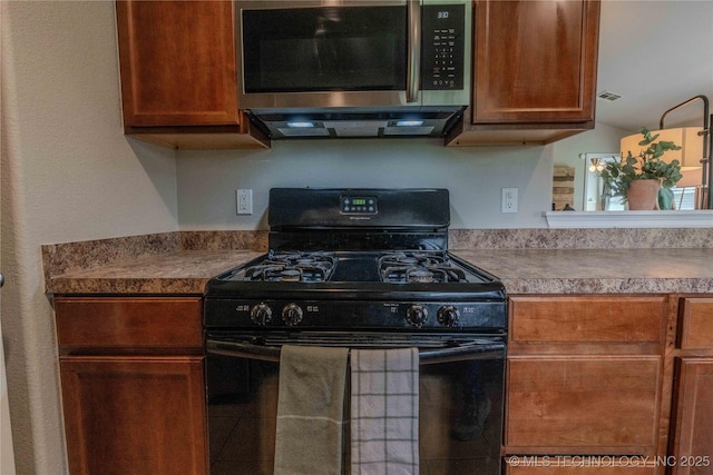 2800 N 20th St, Broken Arrow, OK 74012 - kitchen with gas stove, stainless steel microwave, and brown cabinets