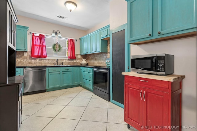 700 D St NW, Ardmore, OK 73401 - kitchen with appliances with stainless steel finishes, decorative backsplash, dark countertops, and light tile patterned floors