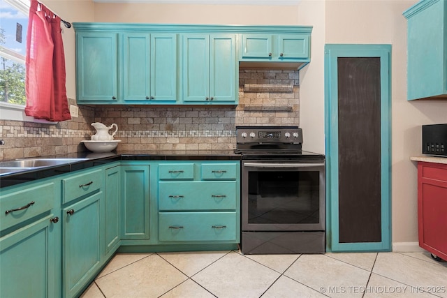 700 D St NW, Ardmore, OK 73401 - kitchen with stainless steel electric range, light tile patterned floors, decorative backsplash, and dark countertops