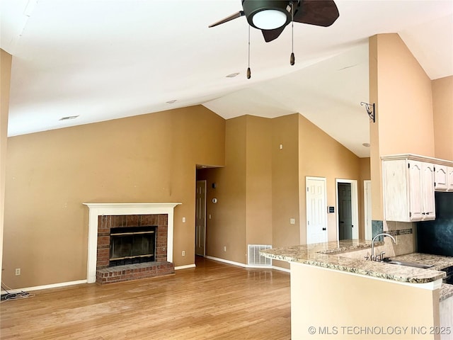 915 Aspenwood St, Cleveland, OK 74020 - kitchen featuring ceiling fan, a sink, light wood finished floors, light stone counters, and high vaulted ceiling