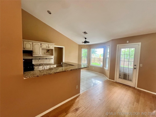 915 Aspenwood St, Cleveland, OK 74020 - kitchen featuring ceiling fan, stone counters, a peninsula, baseboards, and vaulted ceiling