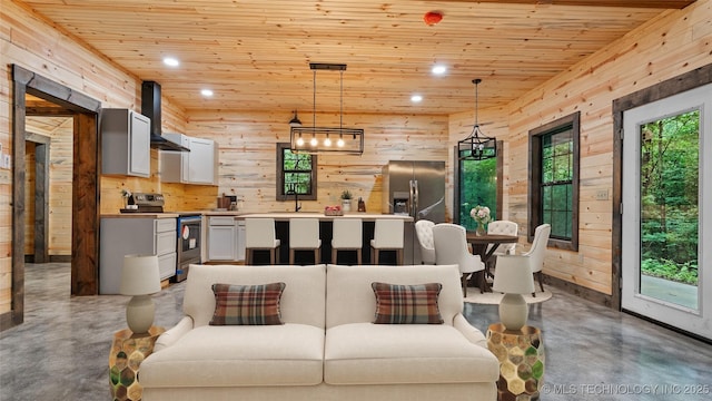 4396 E Cheadle Rd, Milburn, OK 73450 - kitchen with appliances with stainless steel finishes, wall chimney exhaust hood, finished concrete floors, wooden walls, and wood ceiling