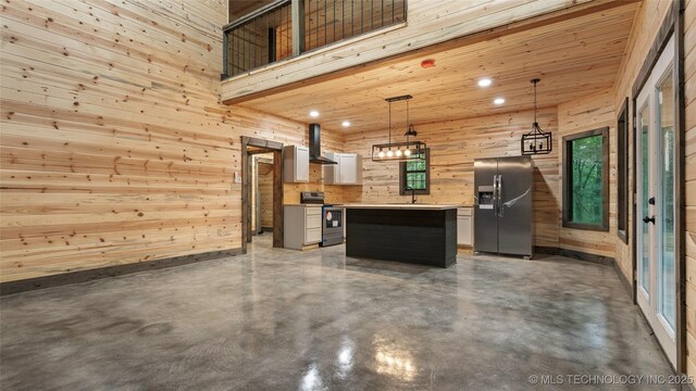 4396 E Cheadle Rd, Milburn, OK 73450 - kitchen featuring stainless steel appliances, wall chimney exhaust hood, wooden walls, finished concrete floors, and a kitchen island