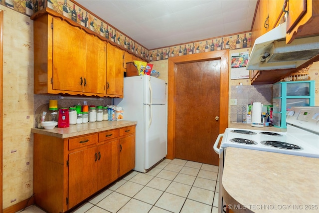200 S K St, Quinton, OK 74561 - kitchen with white appliances, light countertops, under cabinet range hood, brown cabinetry, and light tile patterned flooring