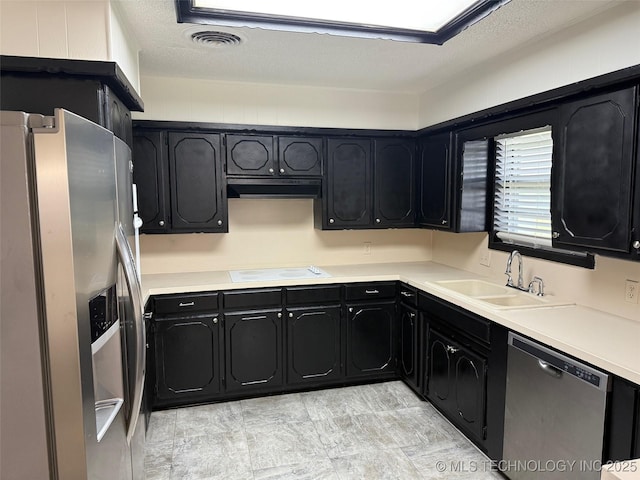 1950 Cimmaron, Wilson, OK 73463 - kitchen with stainless steel appliances, dark cabinetry, under cabinet range hood, light countertops, and a textured ceiling