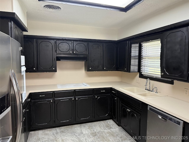 1950 Cimmaron, Wilson, OK 73463 - kitchen with stainless steel appliances, dark cabinets, under cabinet range hood, light countertops, and a textured ceiling