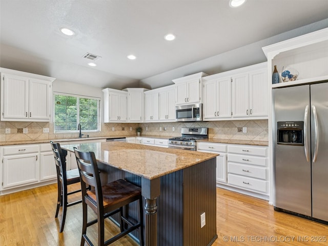 2505 S Willow Ave, Broken Arrow, OK 74012 - kitchen with stainless steel appliances, a center island, white cabinetry, light wood-style floors, and recessed lighting