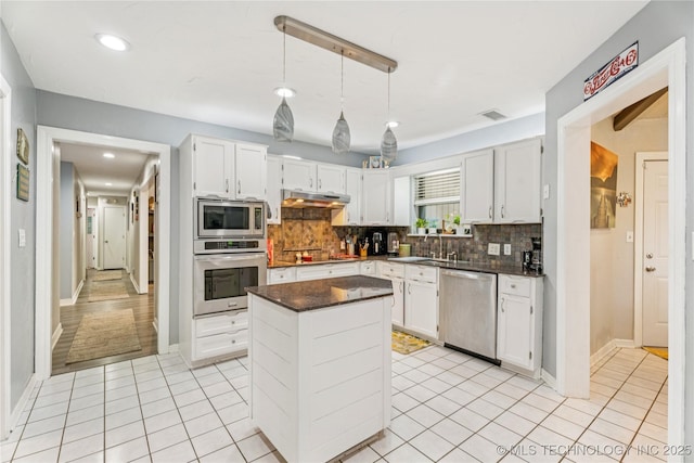 8713 S 77th E Ave, Tulsa, OK 74133 - kitchen featuring stainless steel appliances, under cabinet range hood, dark countertops, a sink, and tasteful backsplash