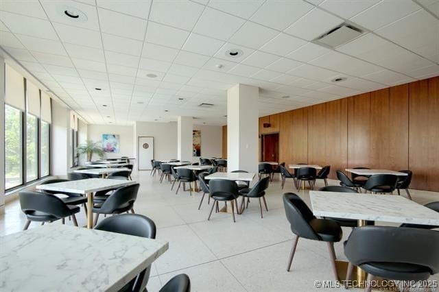 2300 Riverside Dr Unit 5E, Tulsa, OK 74114 - dining area featuring wooden walls, a drop ceiling, and light tile patterned floors