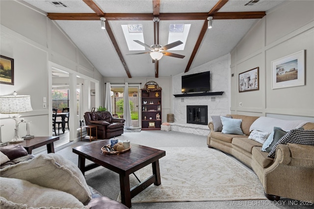 200 Turkey Creek Rd, Bartlesville, OK 74006 - carpeted living area featuring beam ceiling, a skylight, a stone fireplace, a ceiling fan, and high vaulted ceiling