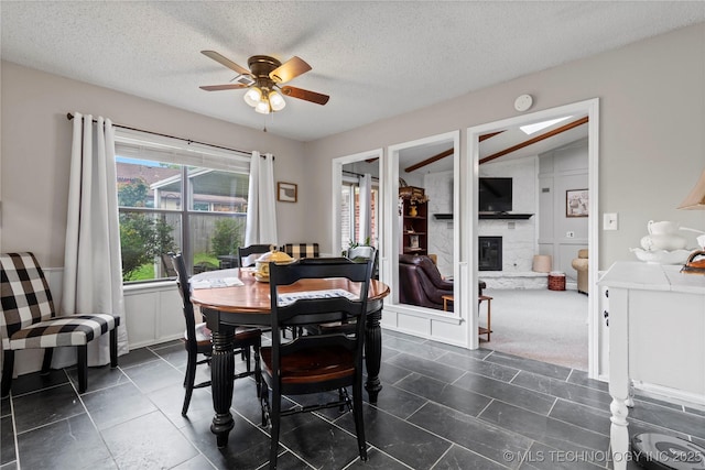 200 Turkey Creek Rd, Bartlesville, OK 74006 - dining area featuring a ceiling fan, a glass covered fireplace, a textured ceiling, and dark tile patterned floors