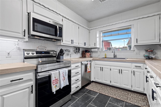 200 Turkey Creek Rd, Bartlesville, OK 74006 - kitchen featuring appliances with stainless steel finishes, a sink, a textured ceiling, white cabinetry, and light countertops