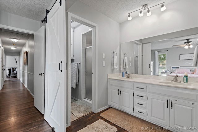 200 Turkey Creek Rd, Bartlesville, OK 74006 - bathroom with a textured ceiling, double vanity, wood finished floors, a stall shower, and a ceiling fan